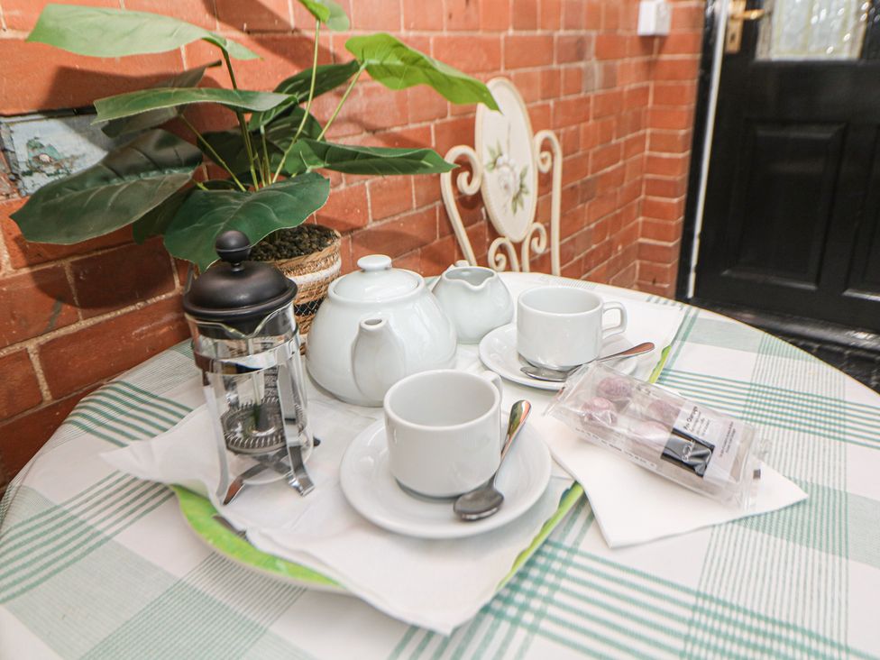 A dining table with tea set and plant at South Lodge - Longford Hall Farm Holiday Cottages Longford near Ashbourne