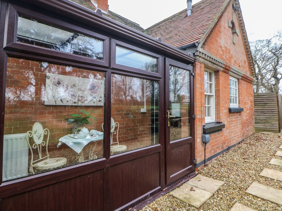 A conservatory with a table and chairs at South Lodge - Longford Hall Farm Holiday Cottages Longford near Ashbourne