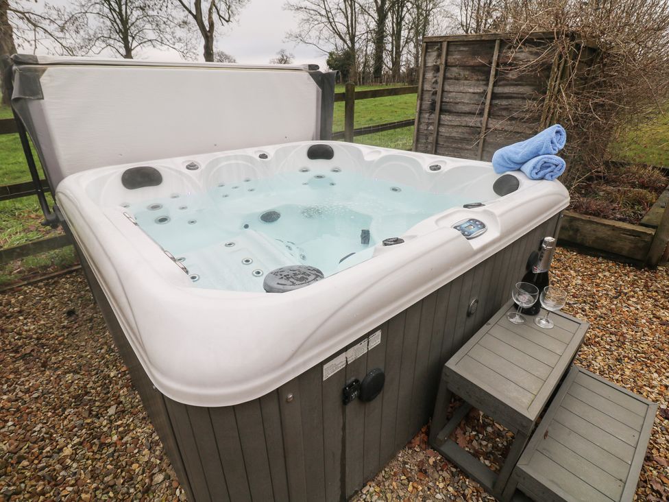 A hot tub with towels and champagne in the garden at South Lodge - Longford Hall Farm Holiday Cottages Longford near Ashbourne