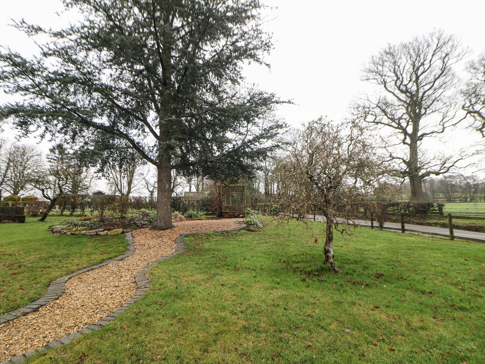 A garden with a pathway and trees at South Lodge - Longford Hall Farm Holiday Cottages in Longford near Ashbourne