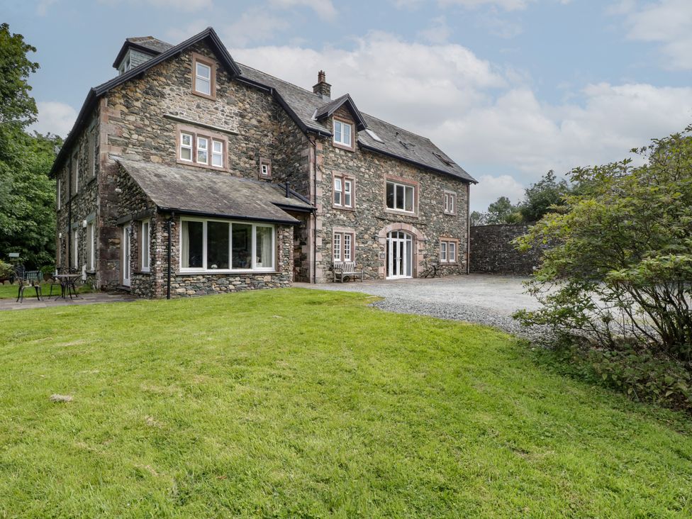 A stone house with a grassy area and parking at High Spy in Keswick