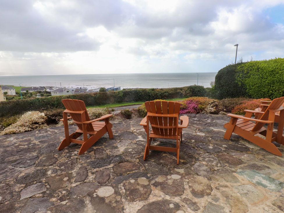 A patio with adirondack chairs overlooking the sea at Bryn Deryn in Criccieth