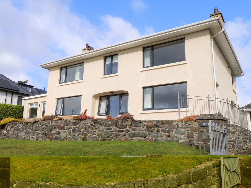 A house with windows and a stone wall at Bryn Deryn in Criccieth