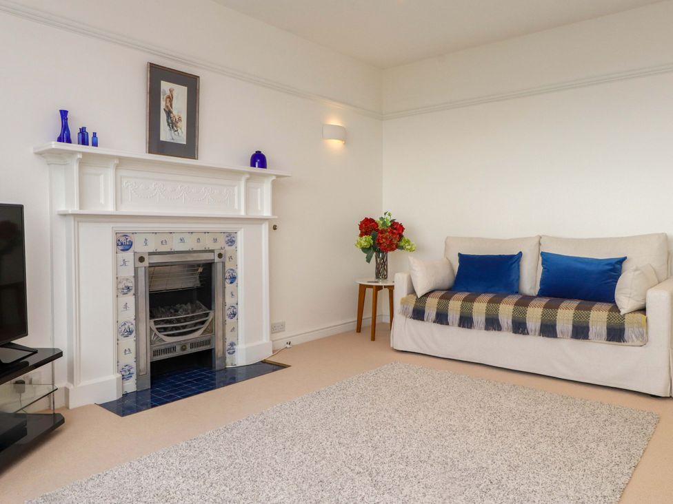 A living room with a fireplace and a sofa at Bryn Deryn in Criccieth