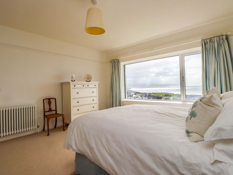 A bedroom with a bed and dresser at Bryn Deryn in Criccieth
