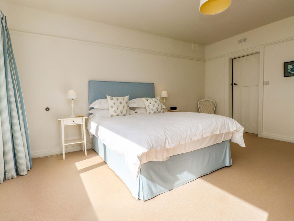 A bedroom with a bed, bedside table, and chair at Bryn Deryn in Criccieth