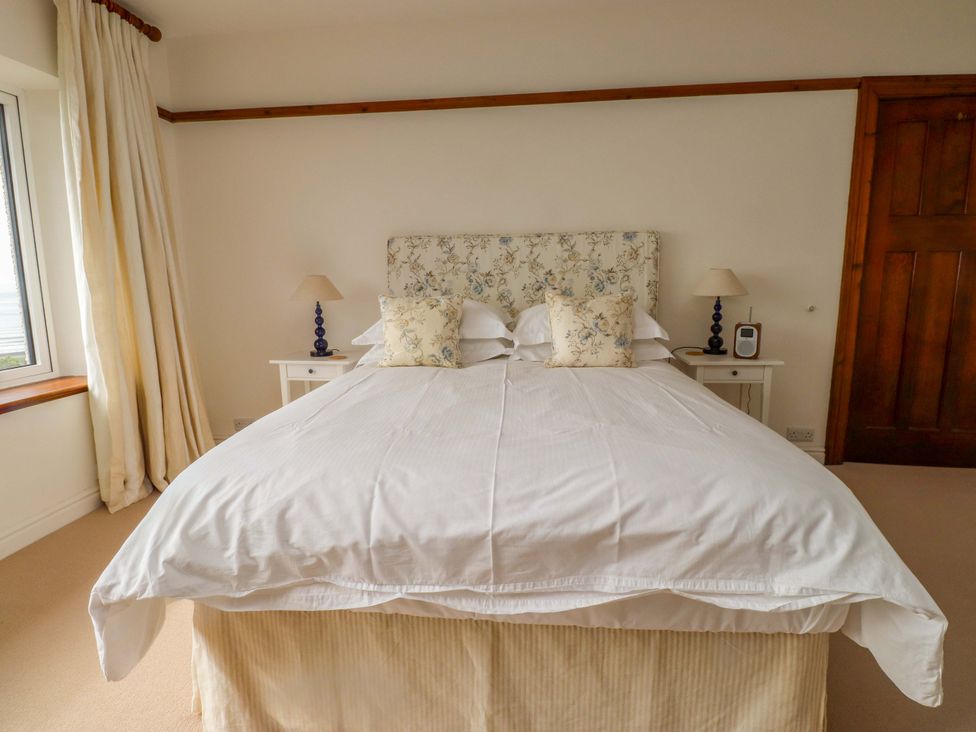 A bedroom with a bed and bedside table at Bryn Deryn in Criccieth