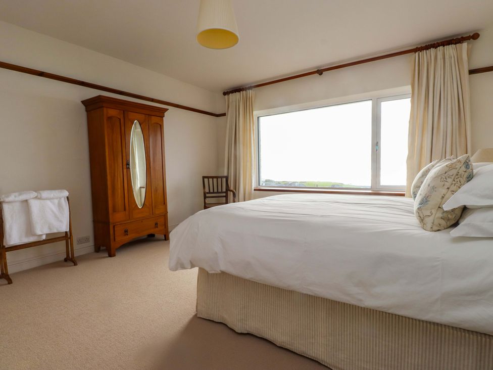 A bedroom with a bed, wardrobe, and window at Bryn Deryn in Criccieth