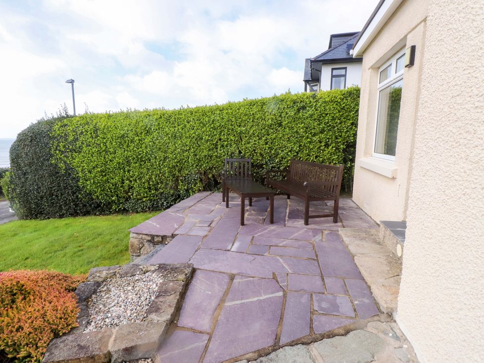 An outdoor area with benches and stone patio at Bryn Deryn in Criccieth