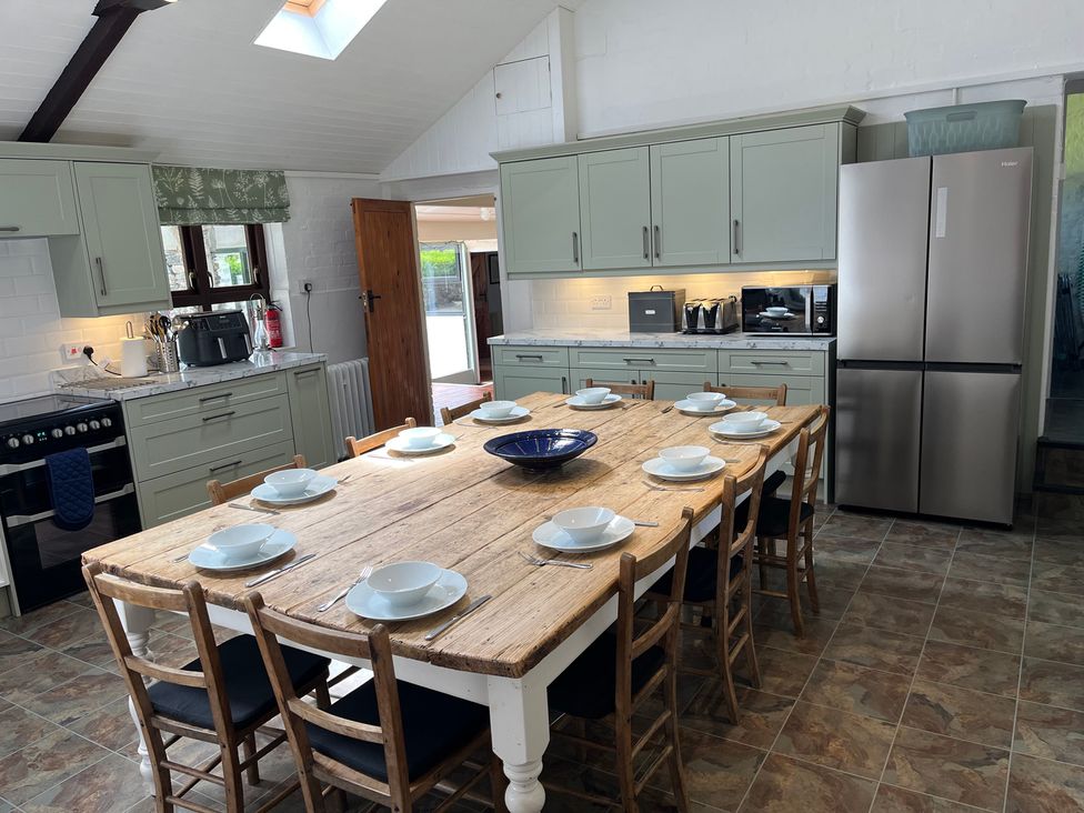 A kitchen with a wooden dining table and refrigerator at Bryn Eira Stables in Llanfair PG