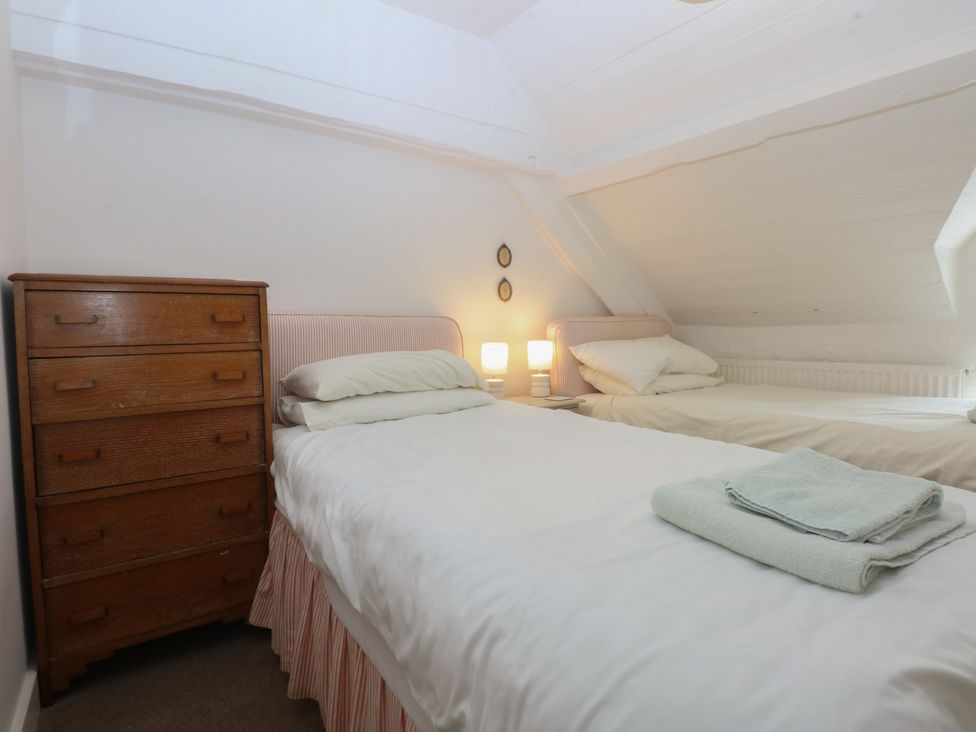 A bedroom with two beds and a chest of drawers at Y Bwthyn in Criccieth