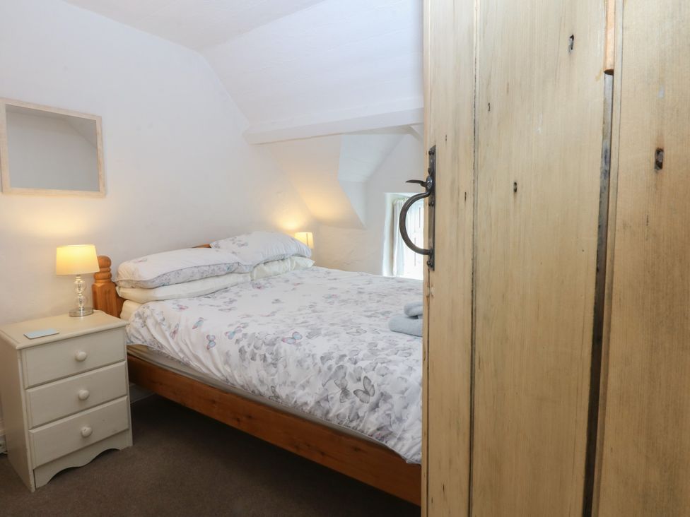 A bedroom with a bed and bedside table at Y Bwthyn Criccieth