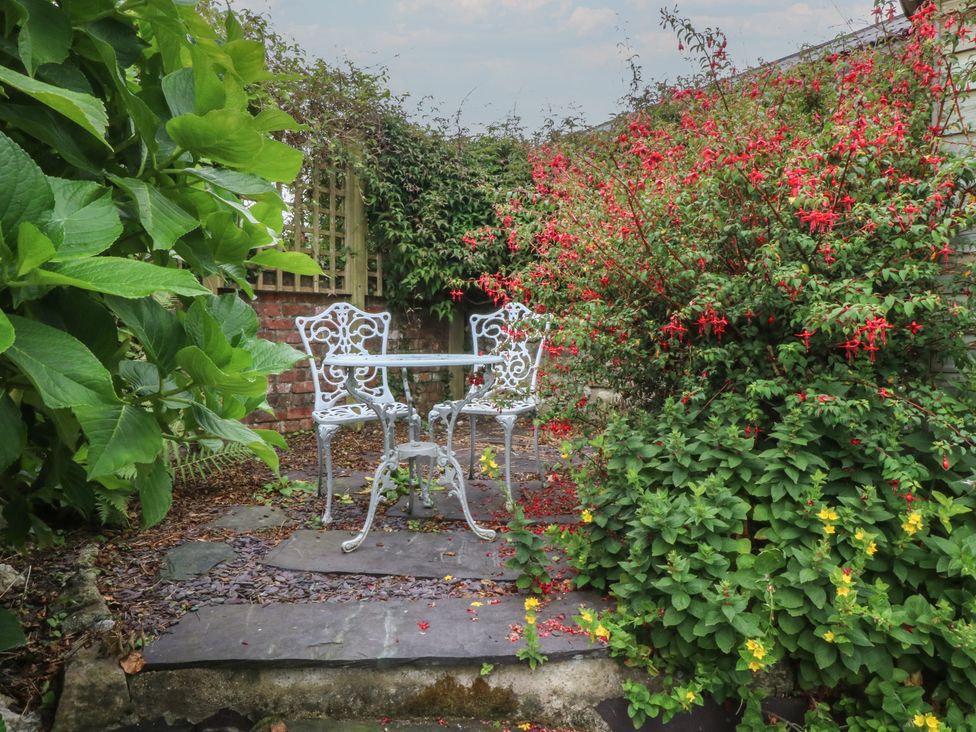 A garden with a table and chairs surrounded by plants at Y Bwthyn in Criccieth