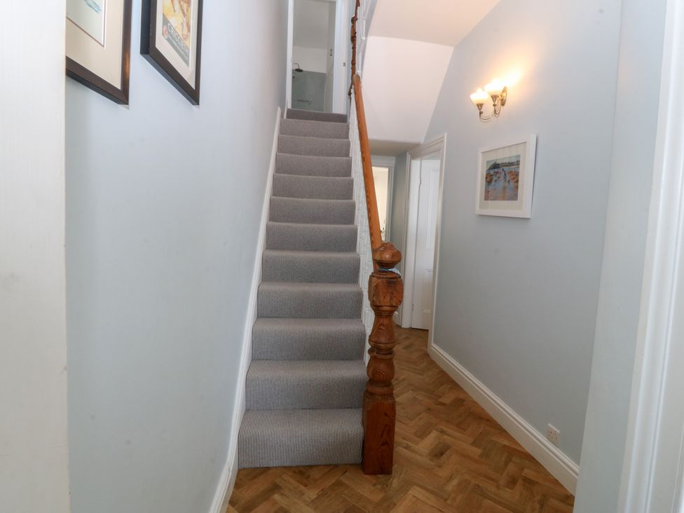 A hallway with stairs and frames at Captain's Rest in Criccieth