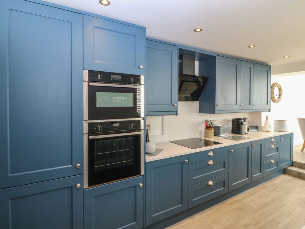 A kitchen with blue cabinets and built-in appliances at Captain's Rest in Criccieth