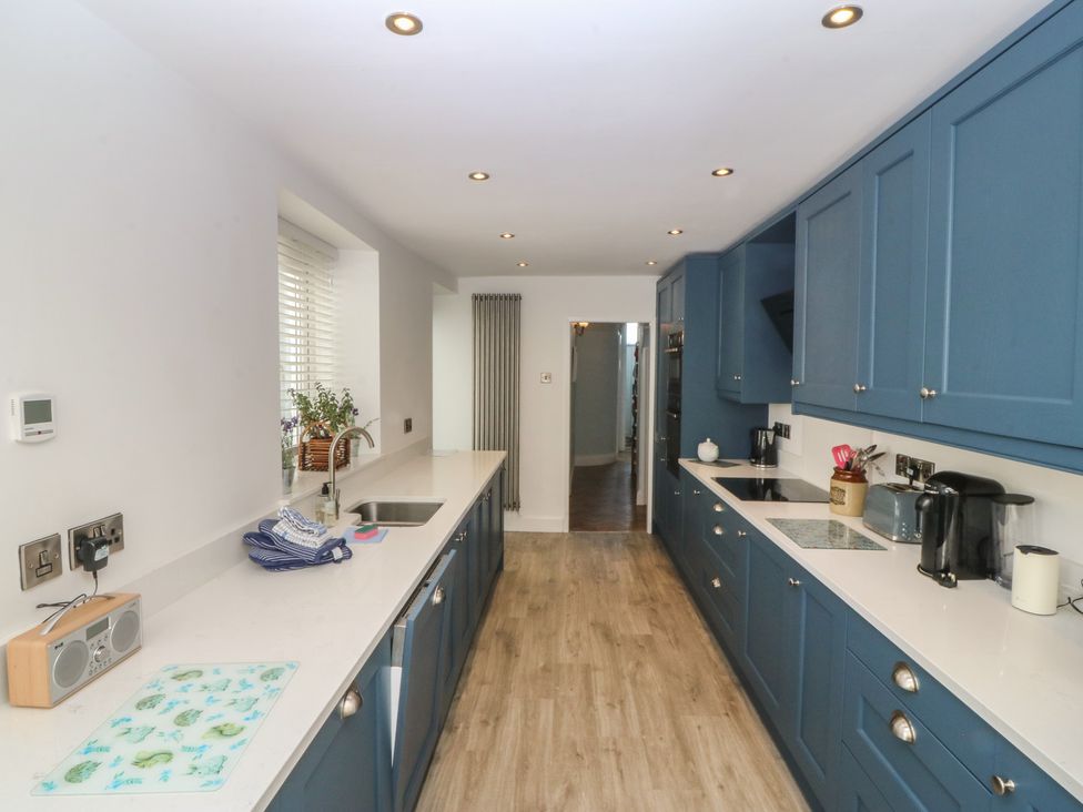 A kitchen with cabinets and appliances at Captain's Rest in Criccieth