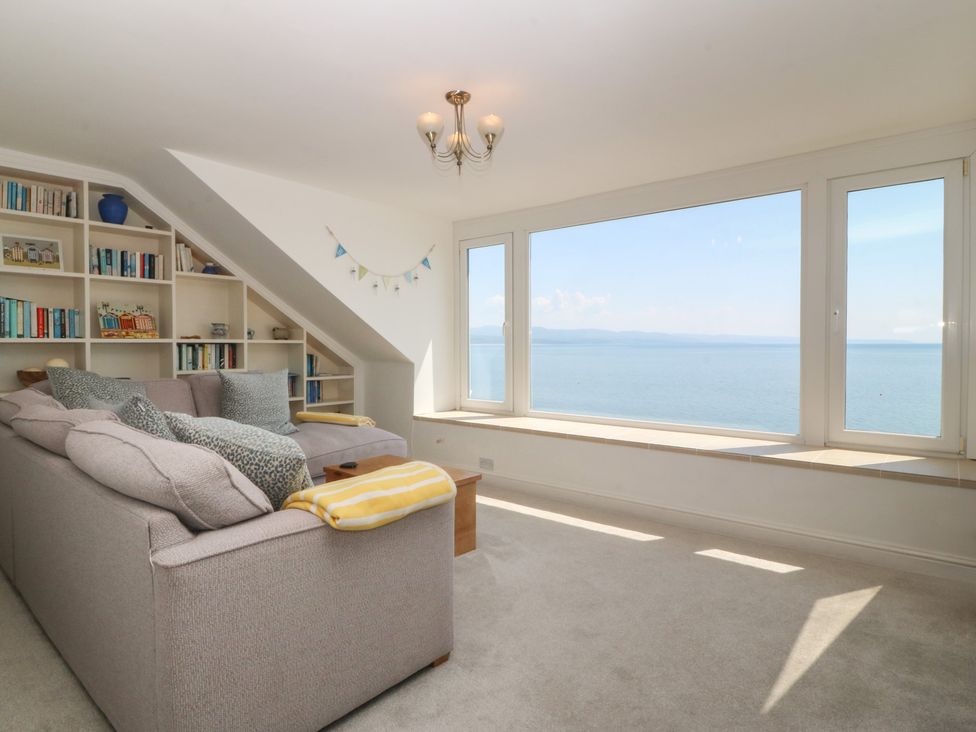 A living room with a sofa and a bookshelf at Captain's Rest in Criccieth