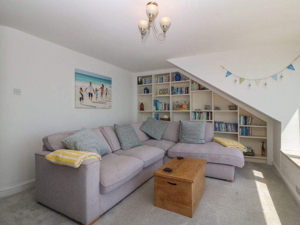 A living room with a sofa and bookshelves at Captain's Rest in Criccieth