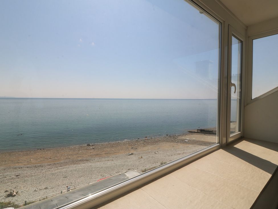 A view from a window overlooking the sea and beach at Captain's Rest in Criccieth