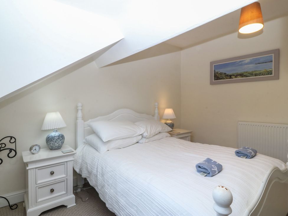 A bedroom with a bed and nightstand at Captain's Rest in Criccieth