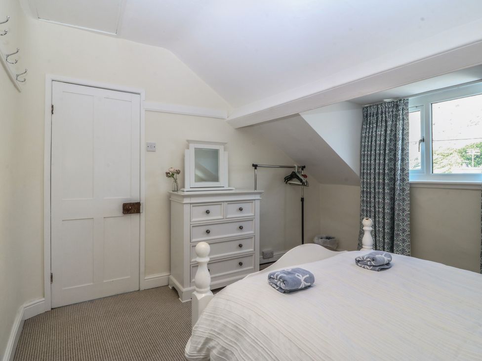 A bedroom with a bed and dresser at Captain's Rest in Criccieth