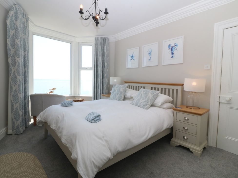 A bedroom with a bed and artwork at Captain's Rest in Criccieth