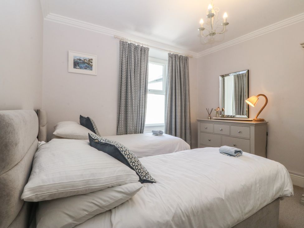 A bedroom with two single beds and a chest of drawers at Captain's Rest in Criccieth