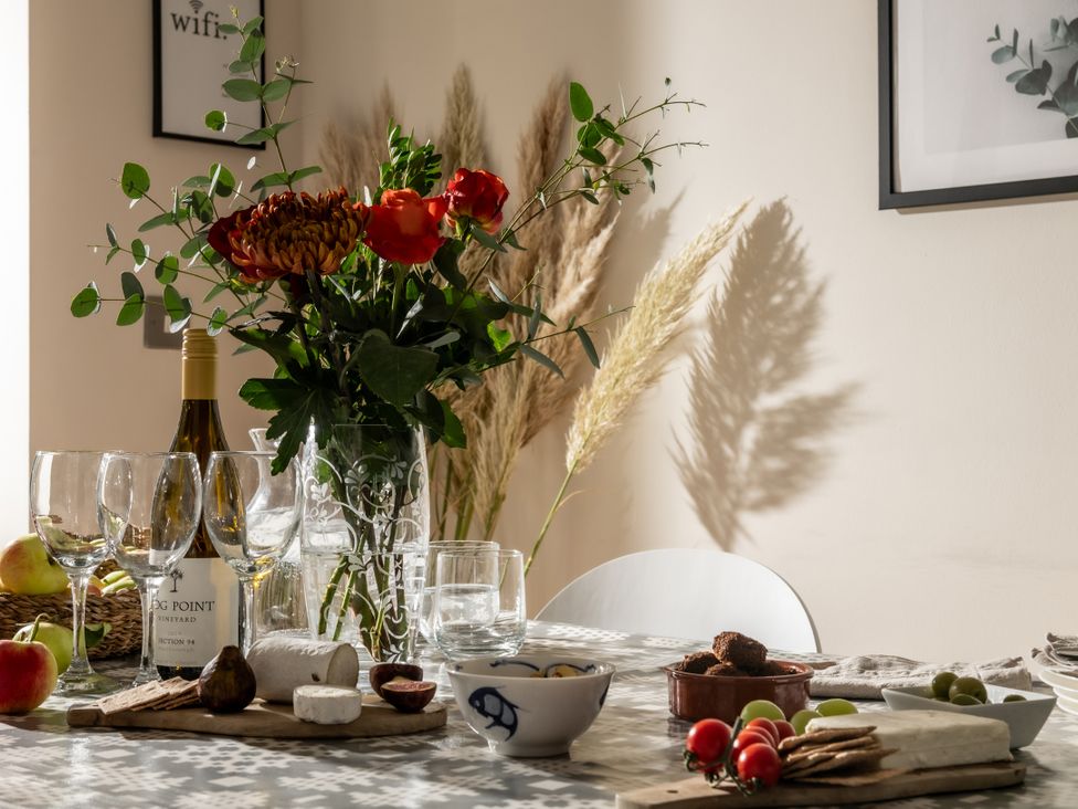 A dining table with wine, cheese, and fruit at Coed y Felin in Conwy