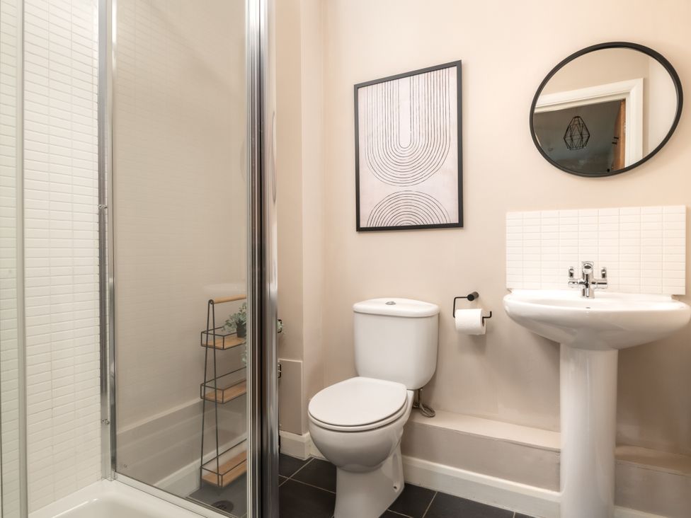 A bathroom featuring a shower, toilet, sink, and wall art at Coed y Felin in Conwy