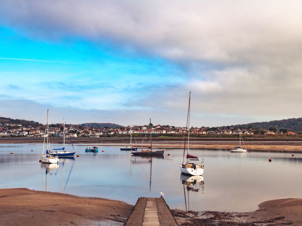 A view of boats on water with a pier and houses in the background at Coed y Felin in Conwy