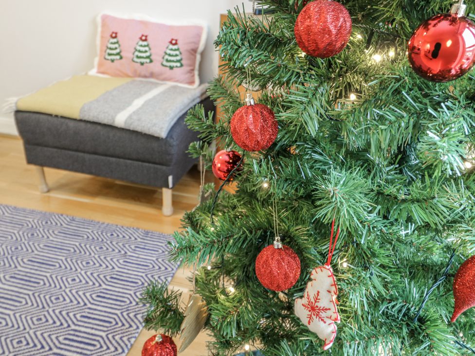 A Christmas tree with ornaments and a footstool at Coed y Felin in Conwy