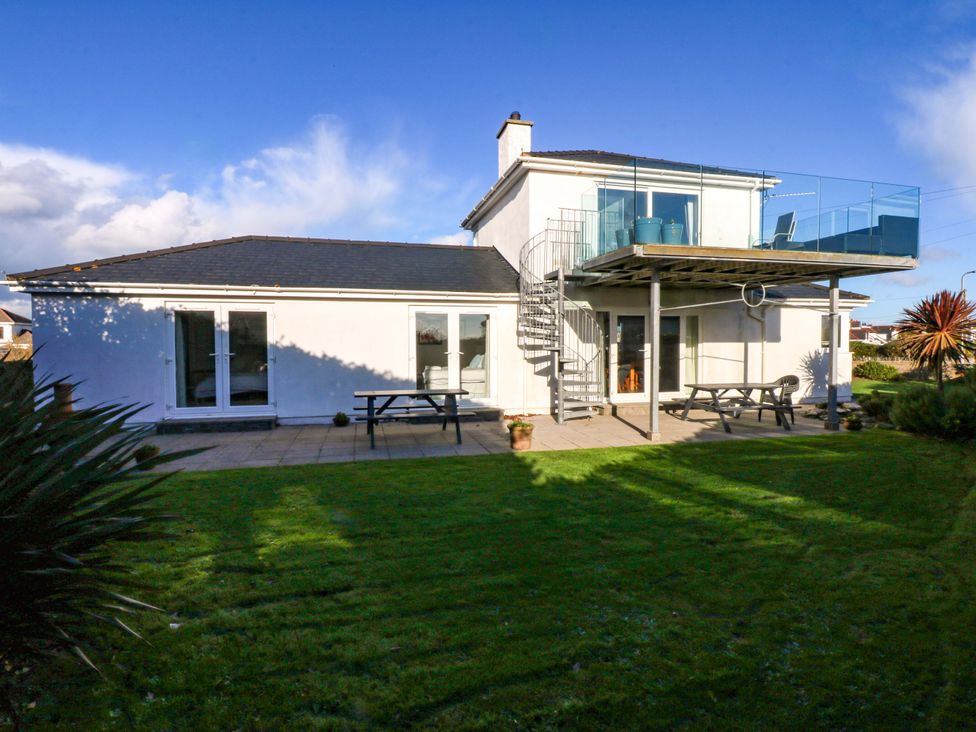 A house with a deck and stairs overlooking a garden at Curragho in Trearddur Bay