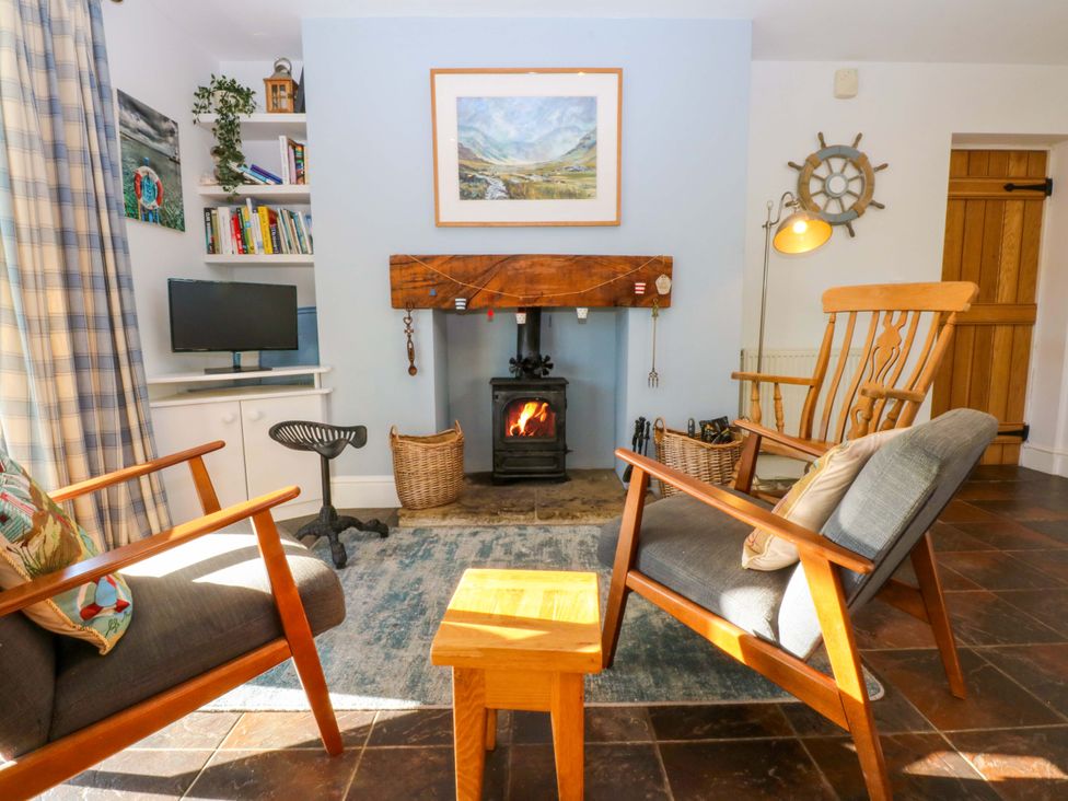 A living room with a fireplace and seating at Curragho in Trearddur Bay