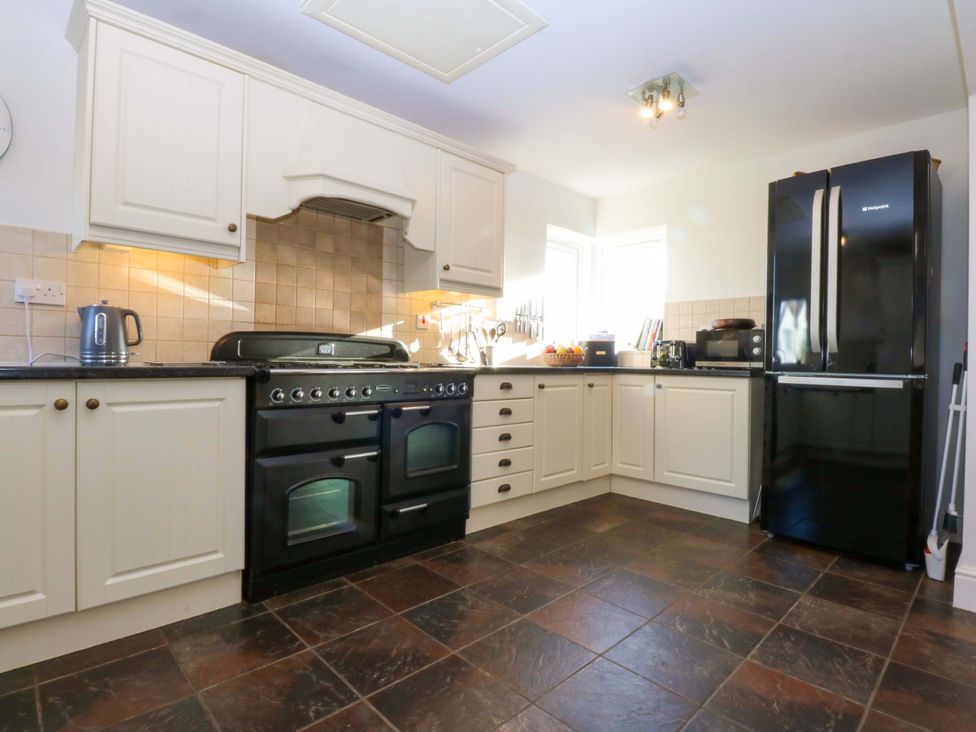 A kitchen with appliances and cabinets at Curragho in Trearddur Bay