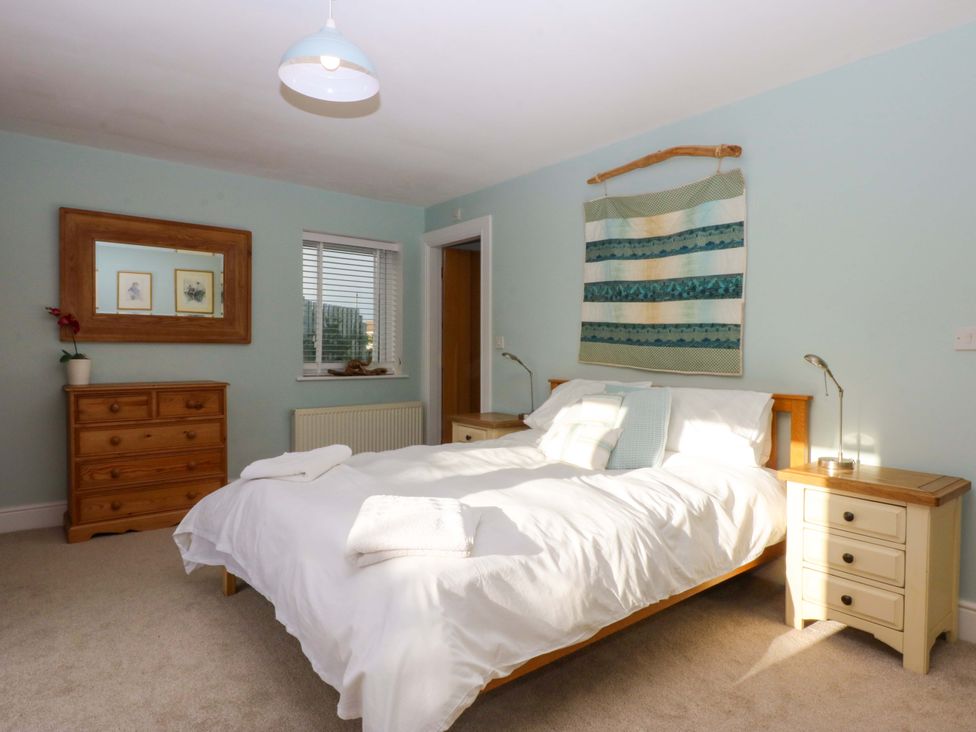 A bedroom with a bed and dresser at Curragho in Trearddur Bay