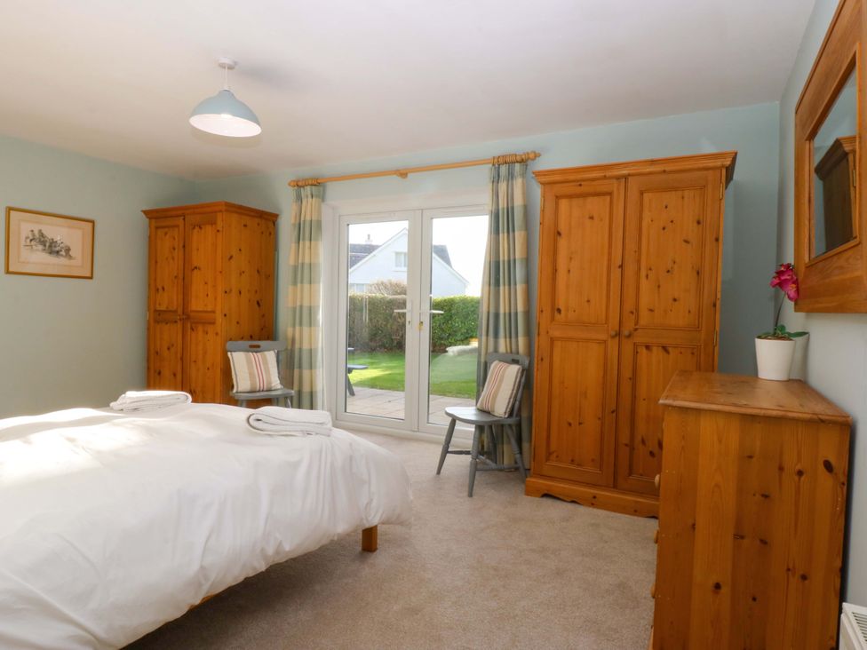 A bedroom with a bed and wardrobes at Curragho in Trearddur Bay