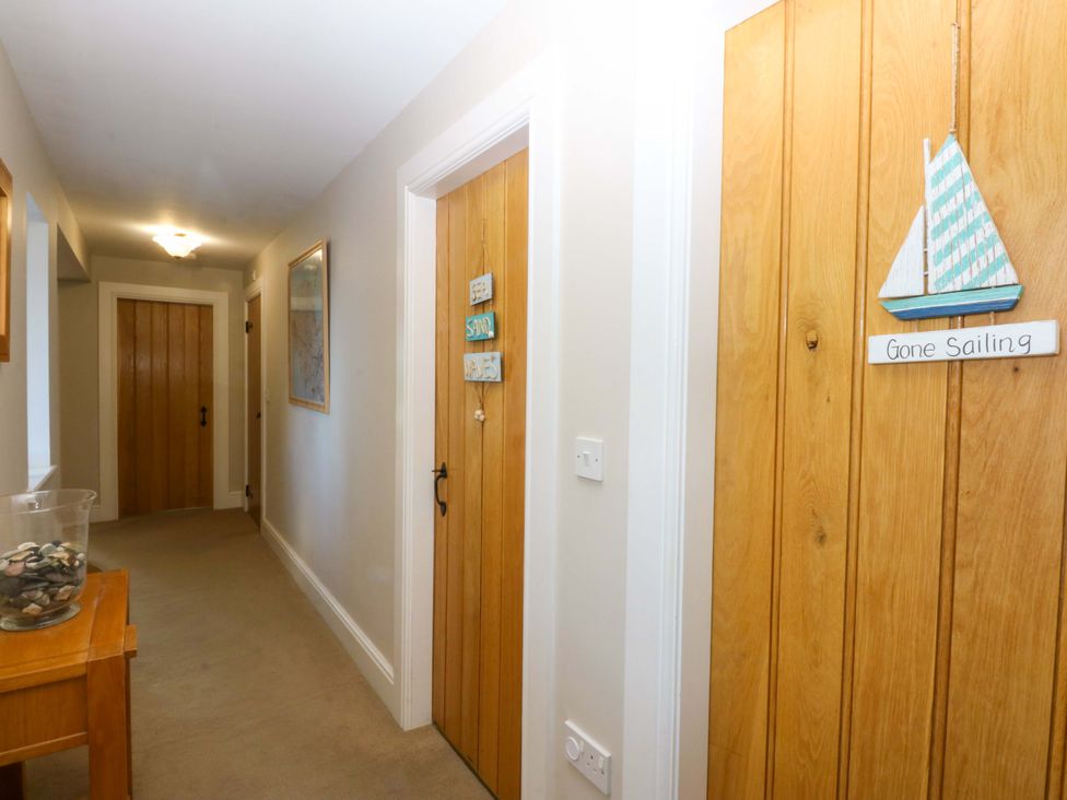 A hallway with wooden doors and a decorative sailboat at Curragho in Trearddur Bay