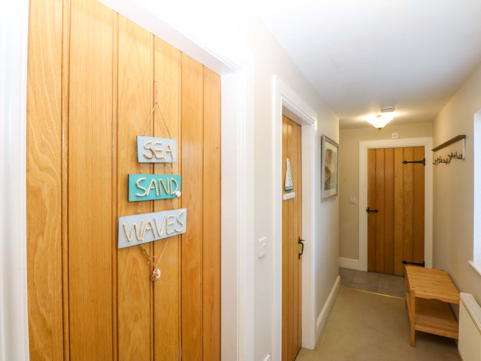 A hallway with wooden doors and decorative signs at Curragho in Trearddur Bay