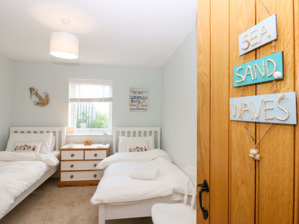 A bedroom with two beds and a dresser at Curragho in Trearddur Bay