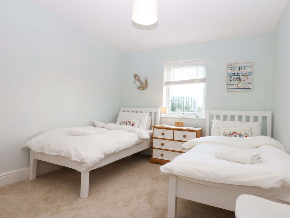 A bedroom with two beds and a chest of drawers at Curragho in Trearddur Bay