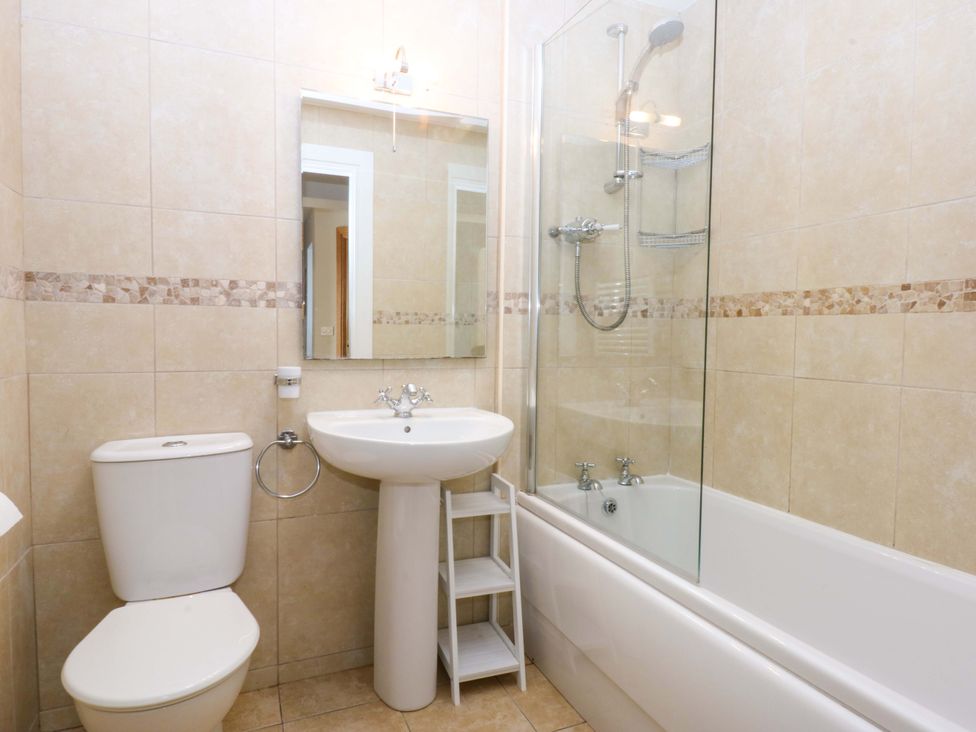 A bathroom with a shower, bathtub, sink, and toilet at Curragho in Trearddur Bay