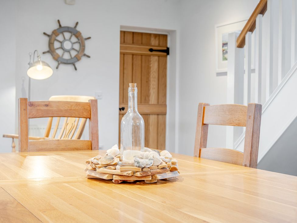 A dining room with a wooden table and chairs at Curragho in Trearddur Bay