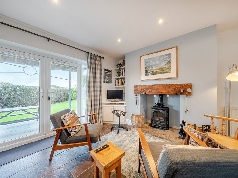 A living room with a fireplace and television at Curragho, Trearddur Bay