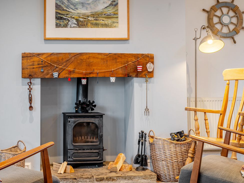 A living room with a fireplace and rocking chair at Curragho Trearddur Bay