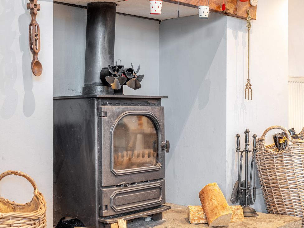 A stove with firewood beside it at Curragho in Trearddur Bay