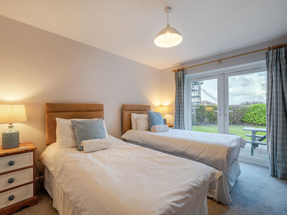 A bedroom with two beds and a window at Curragho in Trearddur Bay