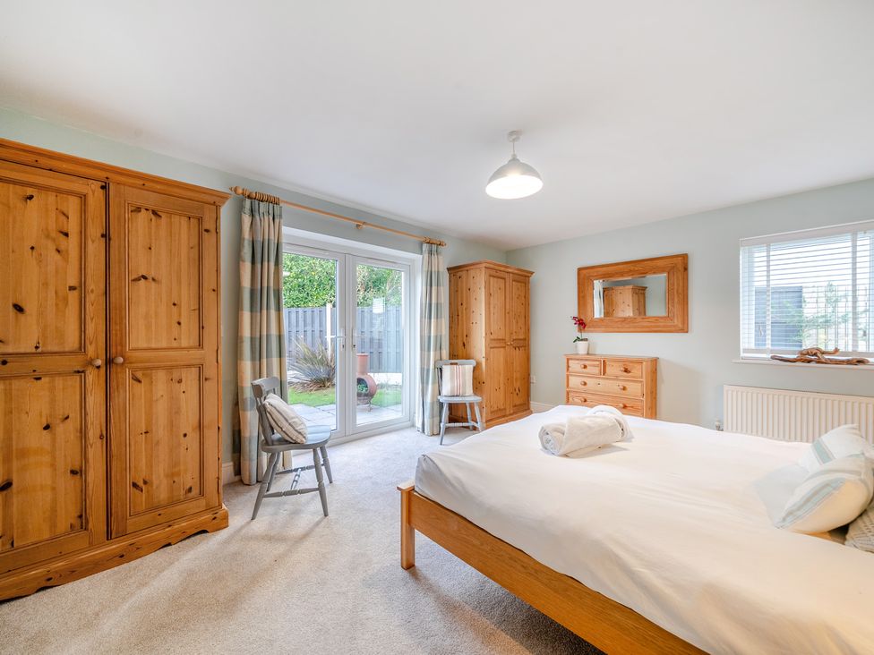 A bedroom with a bed and wardrobe at Curragho in Trearddur Bay
