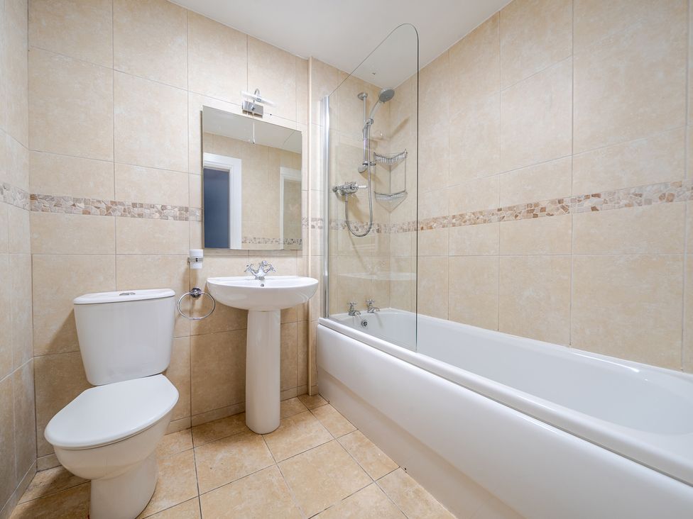 A bathroom with shower, bathtub, sink, and toilet at Curragho in Trearddur Bay