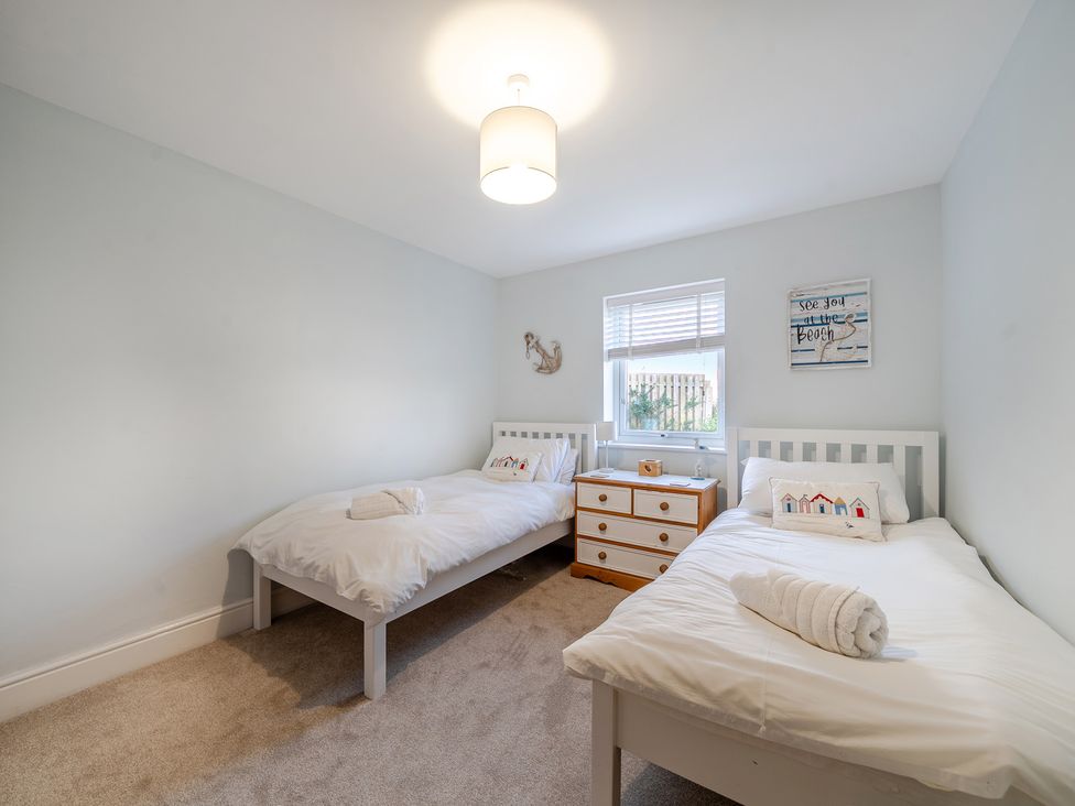 A bedroom with twin beds and a dresser at Curragho in Trearddur Bay