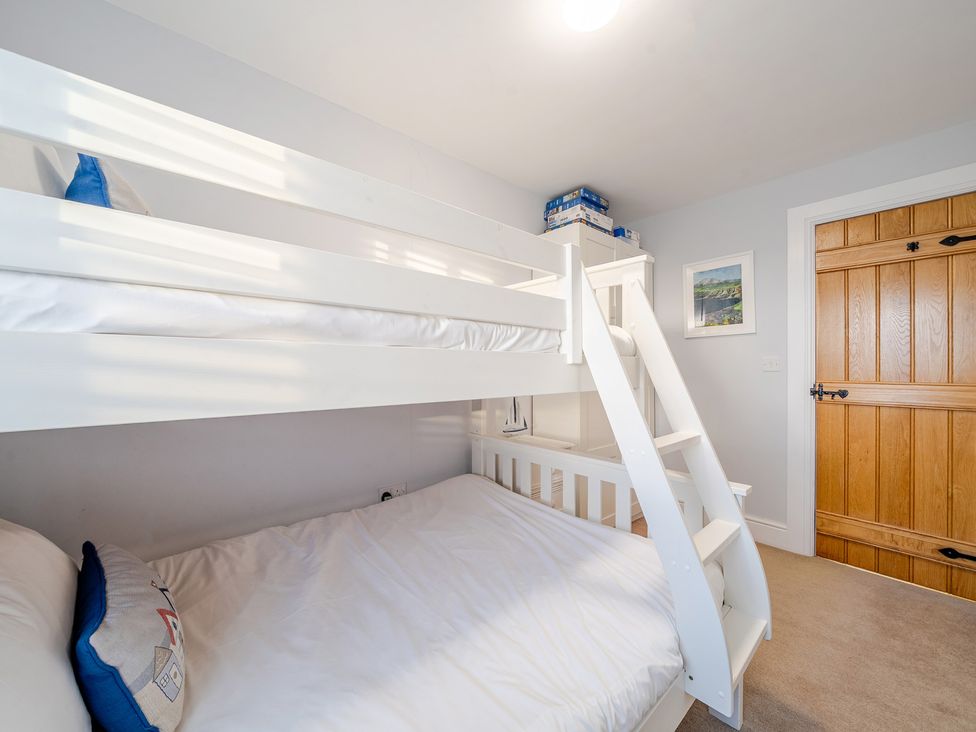 A bedroom with a bunk bed and a wooden door at Curragho in Trearddur Bay